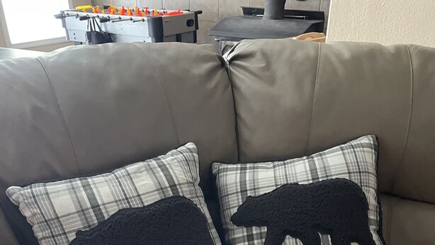 A brown leather sofa with two plaid pillows featuring black bear silhouettes.