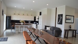 Una cocina moderna con armarios blancos, una mesa de madera larga y taburetes de bar.