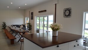 Una cocina moderna con una isla central, bancos de madera y una zona de comedor con sofá.