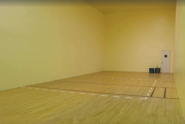 A squash court with a wooden floor and white boundary lines.