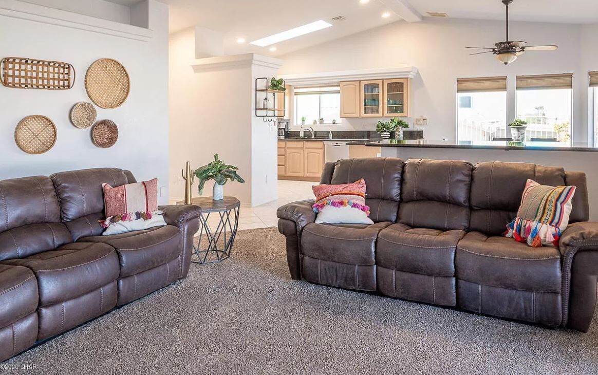 Ein modernes Wohnzimmer mit zwei braunen Ledersofas, einem kleinen runden Tisch und einem Blumentopf.