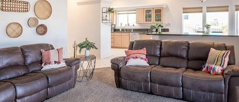 Ein modernes Wohnzimmer mit zwei braunen Ledersofas, einem kleinen runden Tisch und einem Blumentopf.