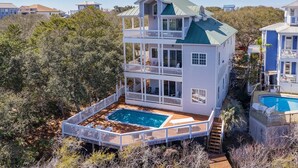 A multi-level house with a pool, surrounded by dense vegetation.