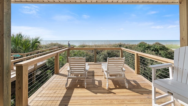A wooden deck with two white Adirondack chairs facing a beach. - "After Dune Delight" oceanfront, 7 bedroom 3 bathrooms (Holden Beach)