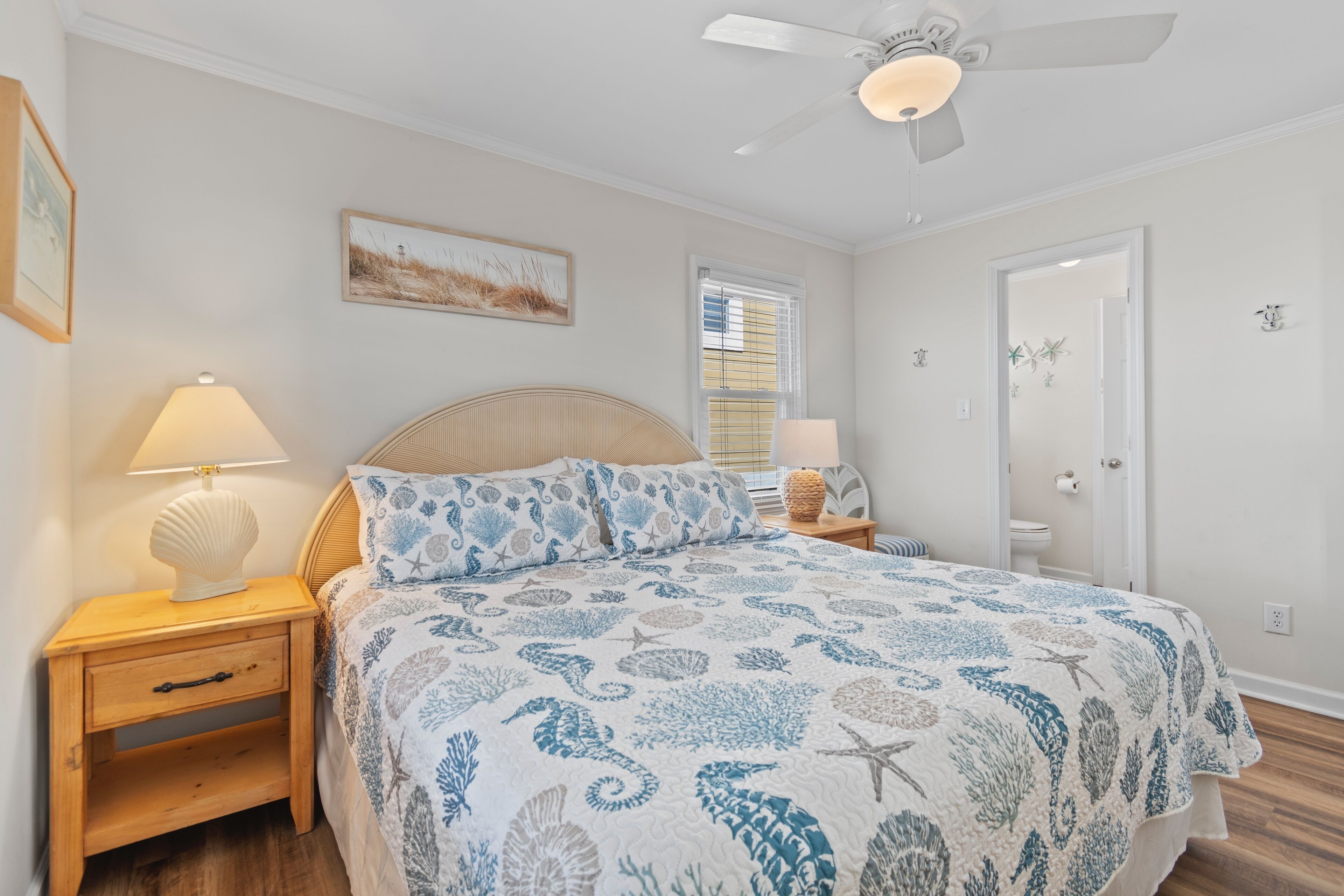 A bedroom with a bed, nightstands, a ceiling fan, and a door.