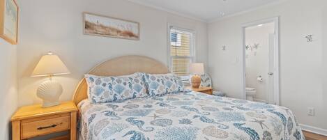 A bedroom with a bed, nightstands, a ceiling fan, and a door.