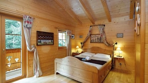 Une pièce en bois avec un lit, deux tables de chevet, une fenêtre et une porte.