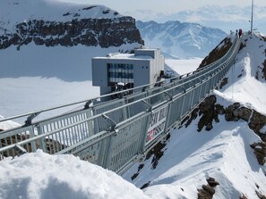 A snow-covered mountain with a metal bridge and a small building.