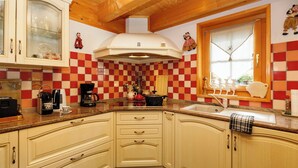 Une cuisine avec un dosseret de carrelage à motifs, des armoires en bois et une fenêtre agrémentée d’objets décoratifs.