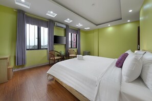A hotel room with a large bed, a desk, a chair, an air conditioner, and a window with curtains. - Golden Lotus Airport Hotel  (Hanoi)