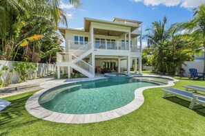 Une maison à deux étages avec une piscine, une terrasse couverte et une pelouse bien entretenue.