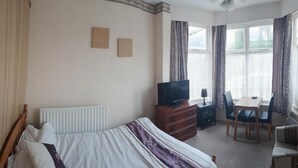 Ein Hotelzimmer mit Bett, Fernseher, Schreibtisch und Stuhl.