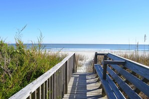 A wooden boardwalk leading to a beach with clear skies.