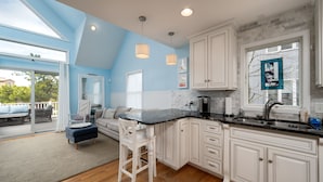 A modern kitchen with white cabinets, a black countertop, and a large window with a stained glass design. - Pet friendly home bay block in Broadkill Beach! 11 California (Milton)