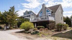 A two-story house with a balcony, surrounded by various shrubs and trees. - Pet friendly home bay block in Broadkill Beach! 11 California (Milton)