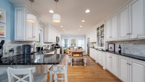 A spacious kitchen with white cabinets, a marble countertop, and a central island with bar stools. - Pet friendly home bay block in Broadkill Beach! 11 California (Milton)