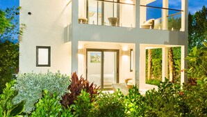 A modern two-story house with a balcony, surrounded by lush greenery. - Villa DelEvan 4C / 1-bedroom villa on the Grace Bay Beach, (Providenciales)
