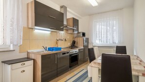 A compact kitchen with modern appliances, a dining area with a table and chairs, and a window with curtains. - Apartment 'Grüne Oase' with Shared Terrace, Shared Garden and Wi-Fi (Friedrichshafen)