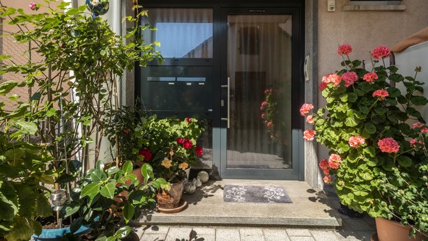 A front entrance with a glass door, potted plants, and a doormat. - Apartment 'Grüne Oase' with Shared Terrace, Shared Garden and Wi-Fi (Friedrichshafen)