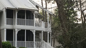 Une maison blanche à deux étages, dotée d’un balcon et d’un porche abrité.