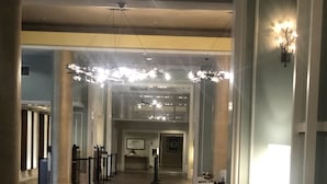 Un hall d’entrée spacieux avec un plancher en bois, un comptoir d’accueil et un lustre.