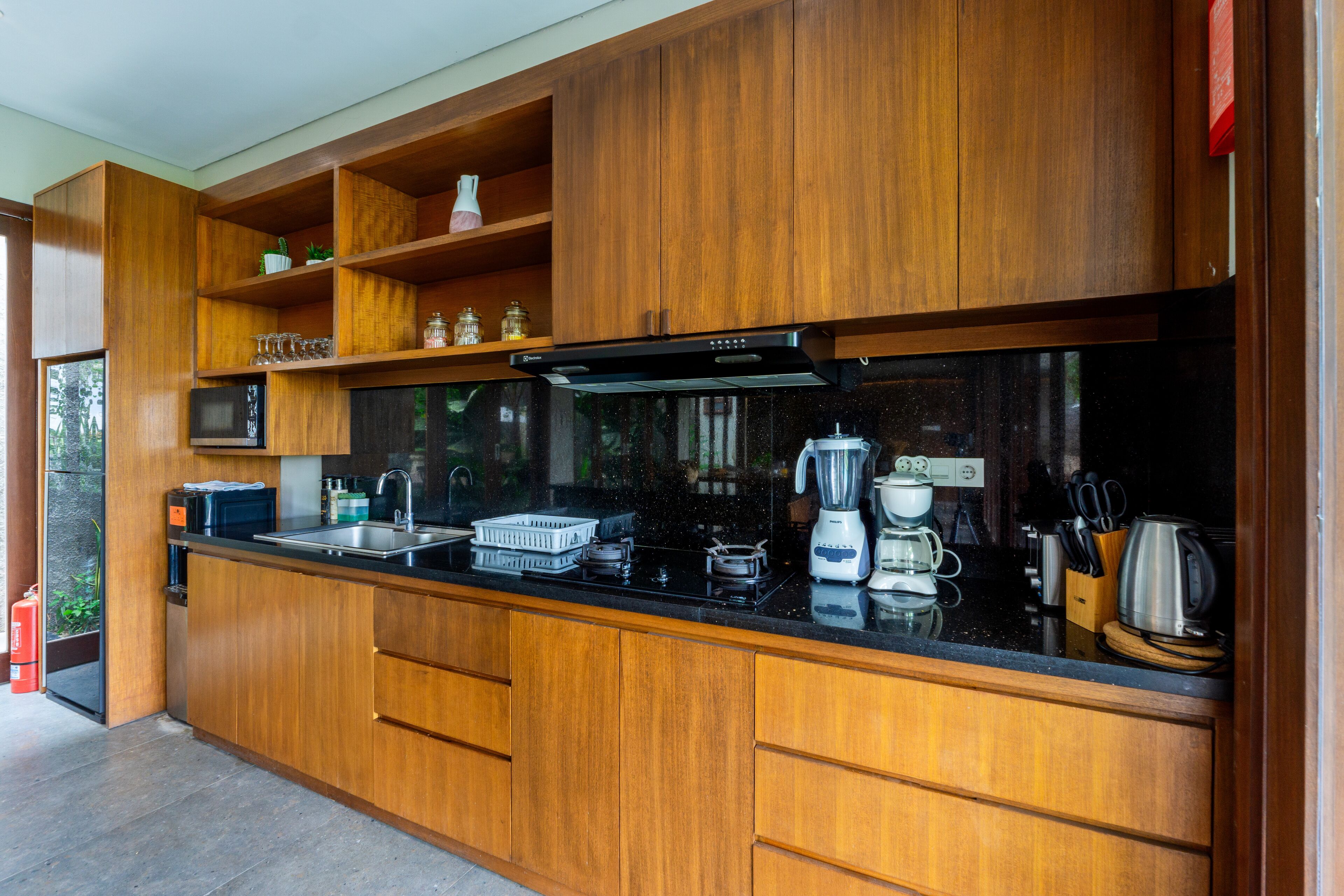 A modern kitchen with wooden cabinets, a black countertop, and various appliances including a microwave, toaster, and coffee maker.