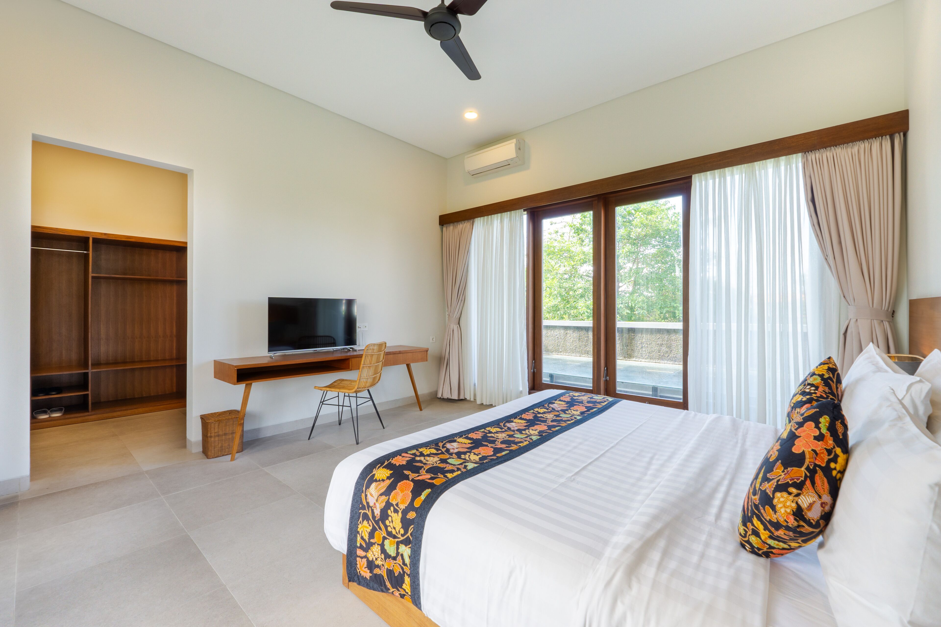 Un dormitorio con cama, escritorio, televisor y armario.