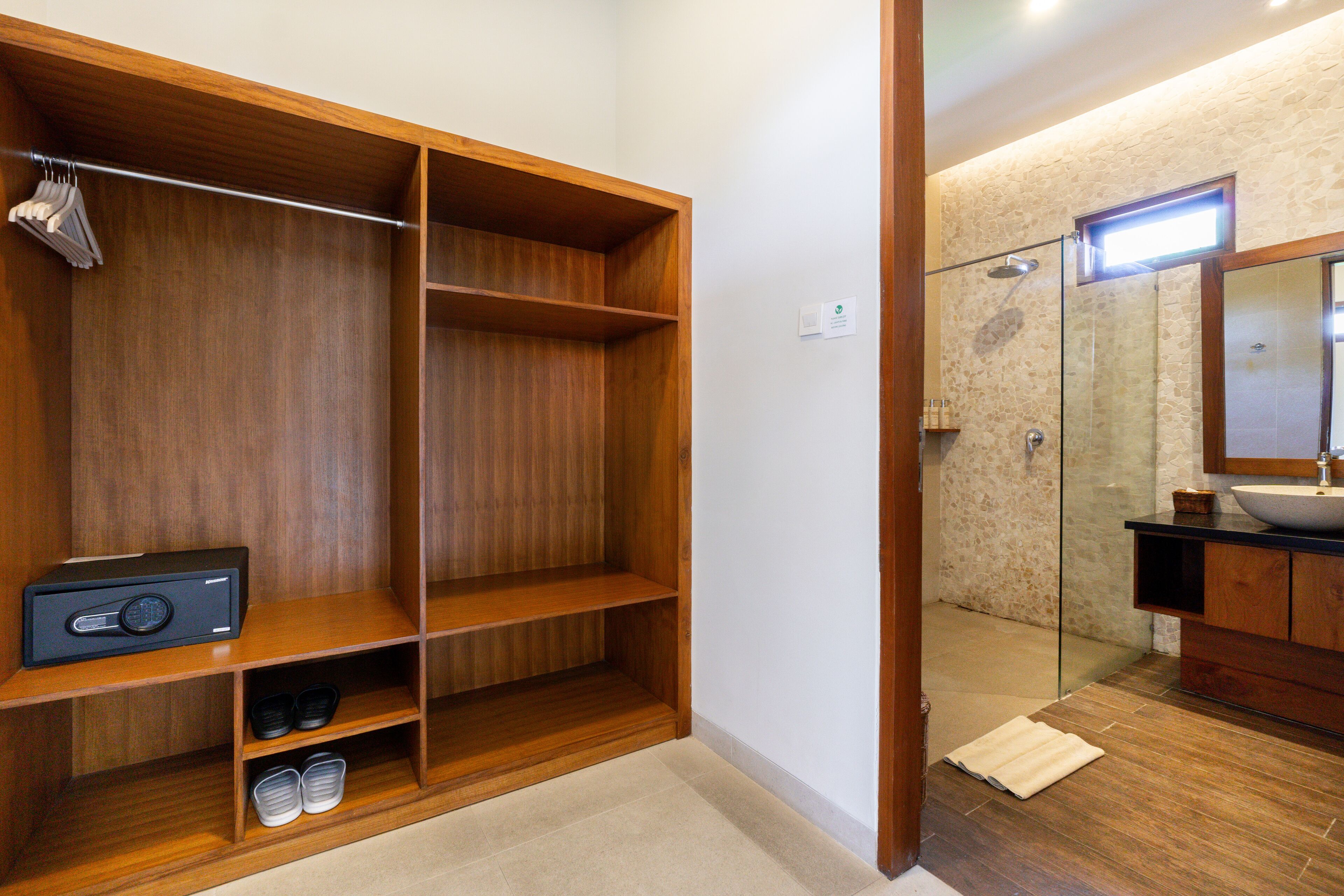 A bathroom with a wooden vanity, a glass shower enclosure, and a built-in shelf unit.