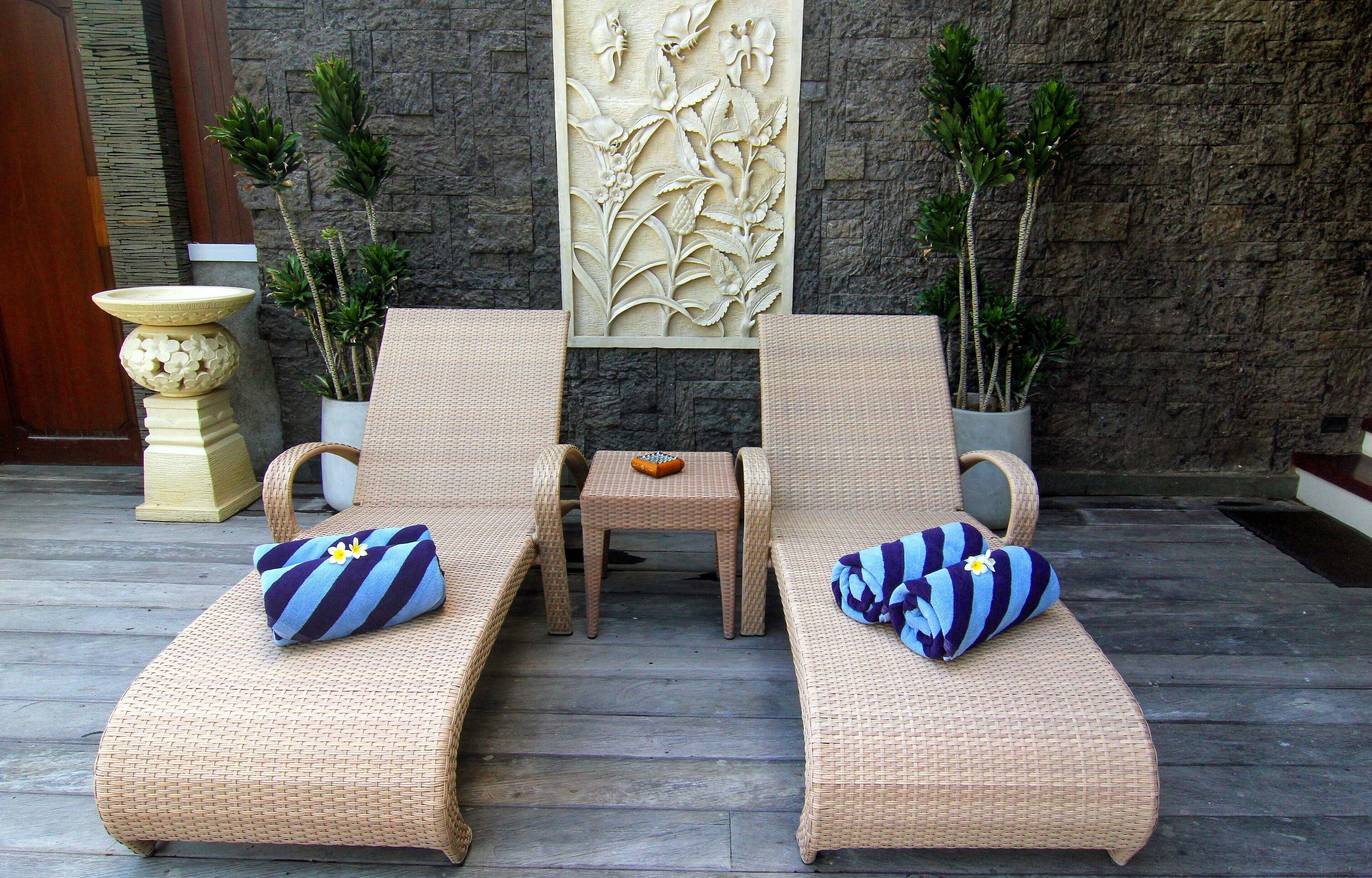 Un espace détente avec deux fauteuils en osier, une petite table et des plantes décoratives.