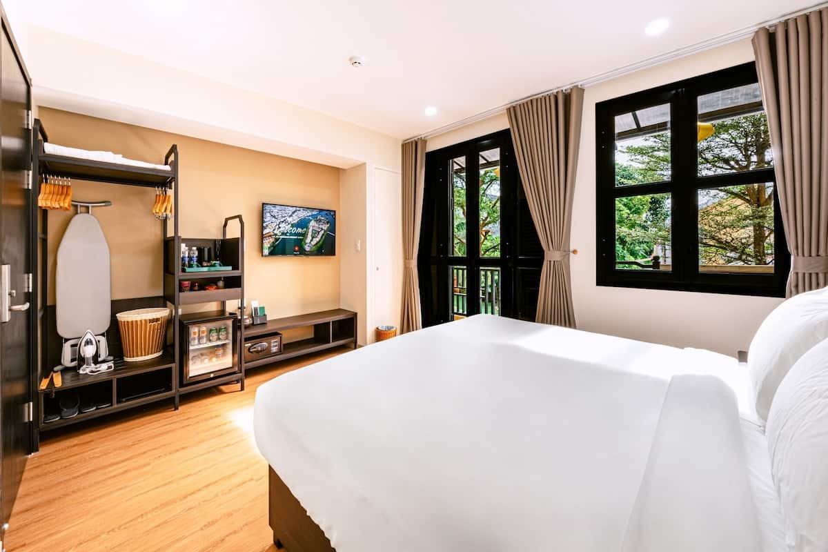 A hotel room with a bed, a TV, a wardrobe, and a window with curtains.