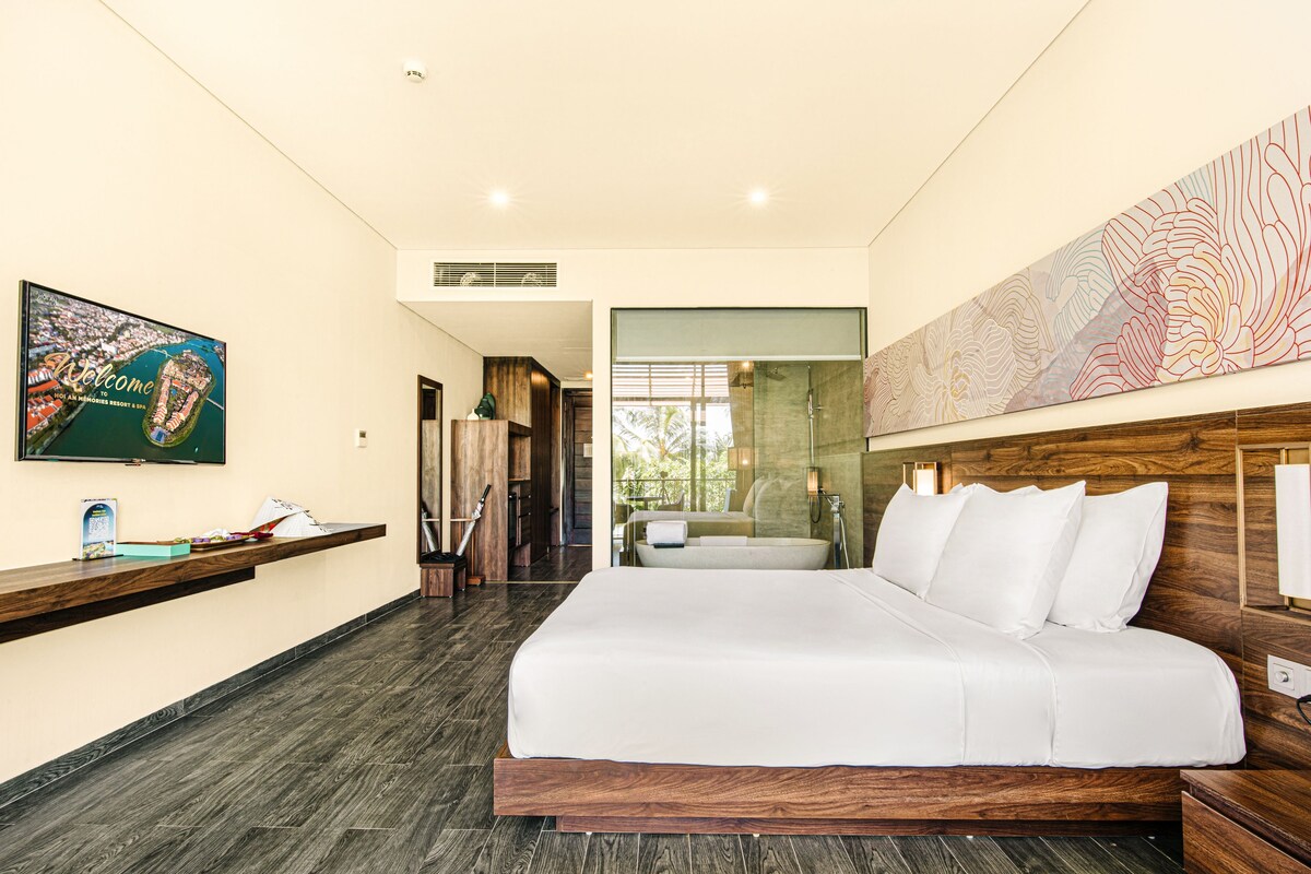 A modern hotel room with a large bed, wooden headboard, a flat-screen TV on the wall, and a wooden reception desk.