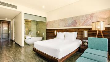 A modern hotel room with a large bed, a sitting area, a bathtub, and a large wall mural.