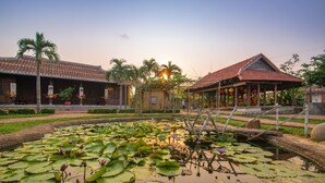 A traditional building with a tiled roof and a garden with a pond and lotus flowers. - Hoi An Memories Resort & Spa (Da Nang)