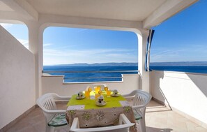 A balcony with a table set for two, overlooking a sea view. - Apartments Nena (Omis)