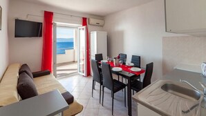 A compact living space with a dining area, kitchenette, and a balcony with a view. - Apartments Nena (Omis)