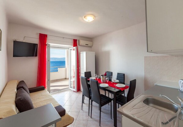 Un espace de vie compact comprenant un coin repas, une kitchenette et un balcon avec vue.