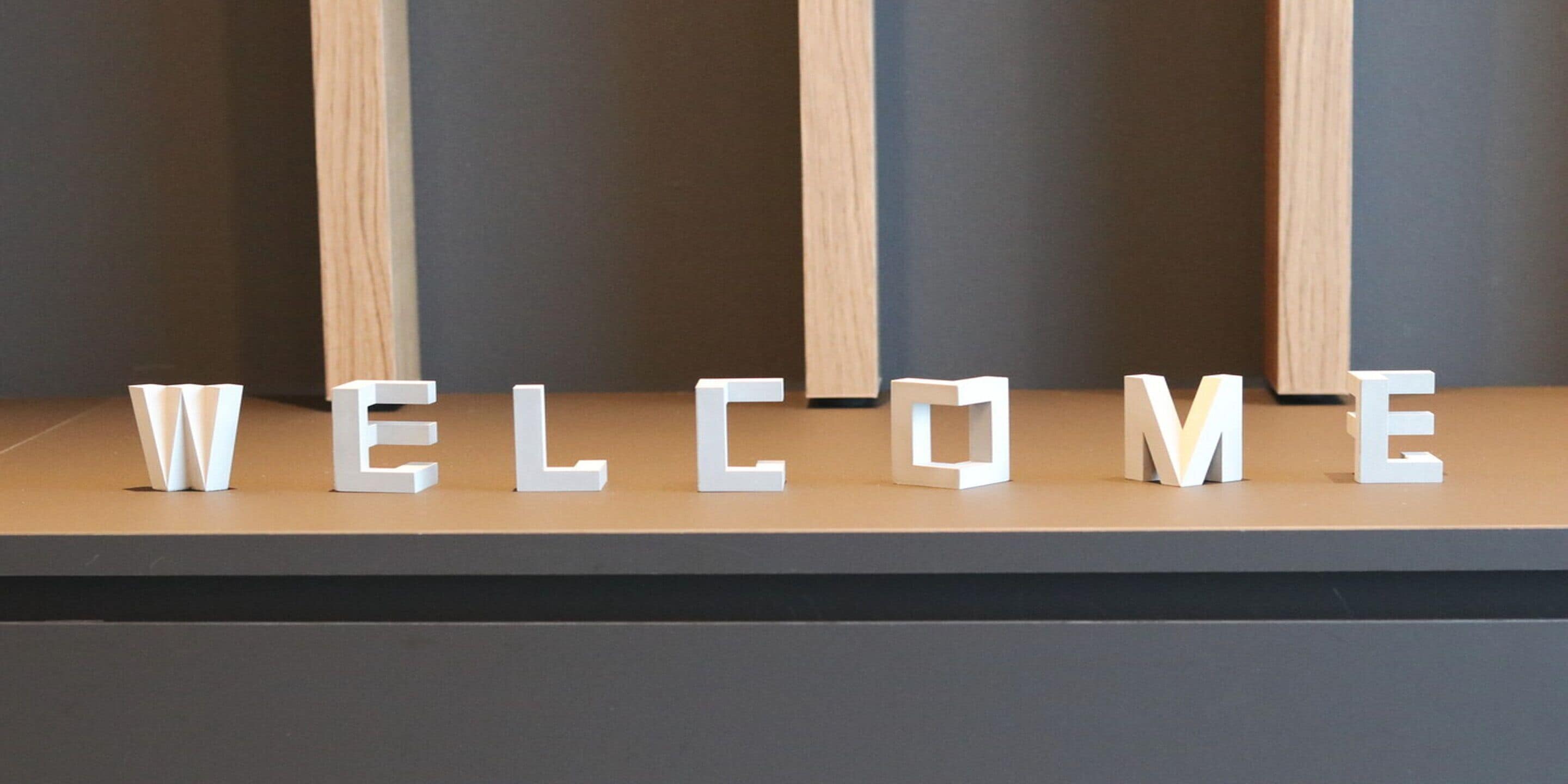 A reception desk with the word "WELCOME" spelled out in white letters on a wooden surface.