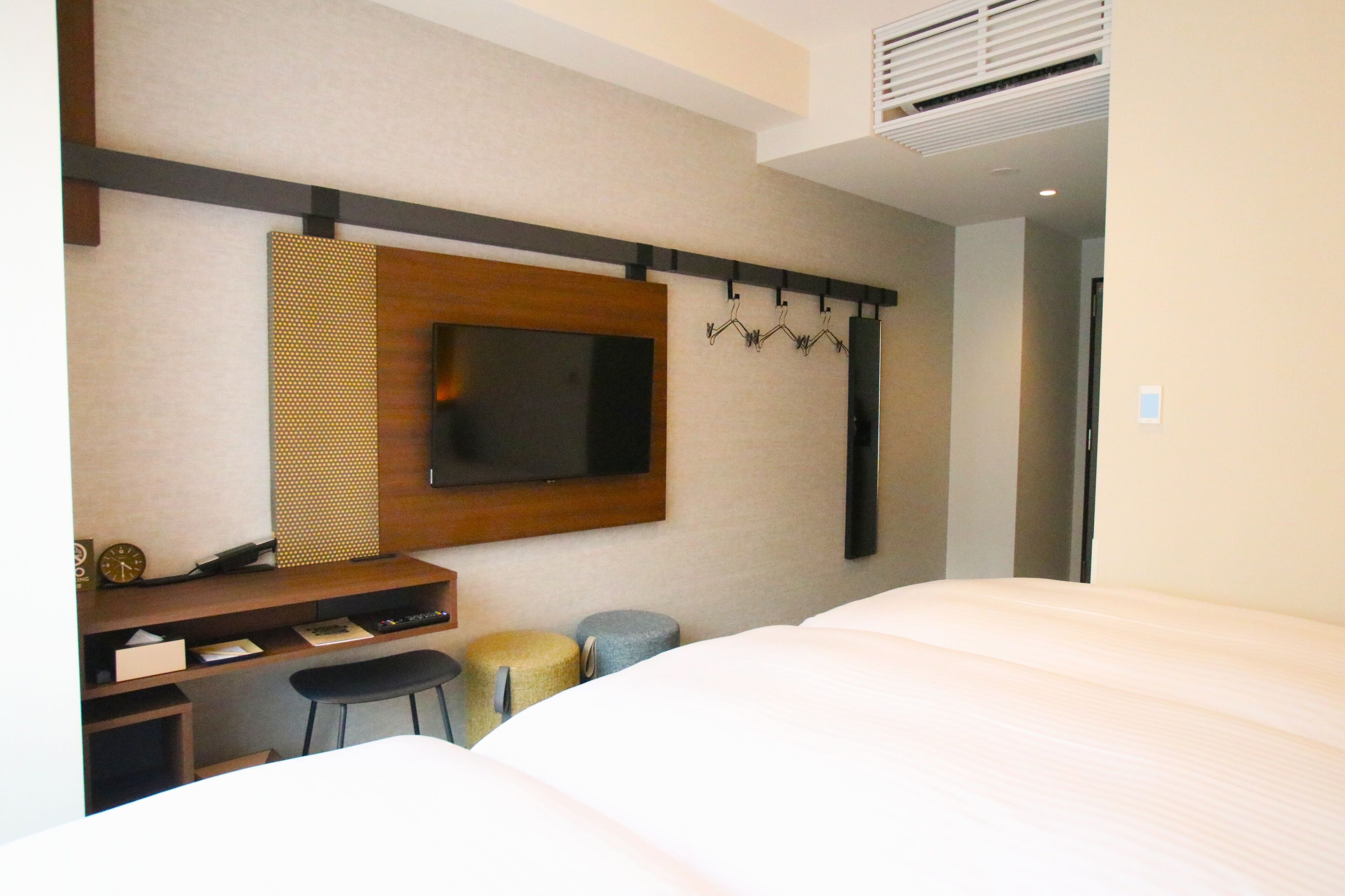 Een hotelkamer met een bed, een bureau met een computer, een stoel en een aan de muur bevestigde televisie.