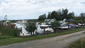 A marina with boats docked, a dirt path, and a grassy area with trees.