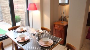 Una mesa de comedor decorada con platos y tazones rosas, un mantel con lunares y una lámpara roja.
