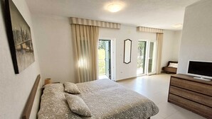 Ett sovrum med en säng, en tv, en byrå och en tavla på väggen.