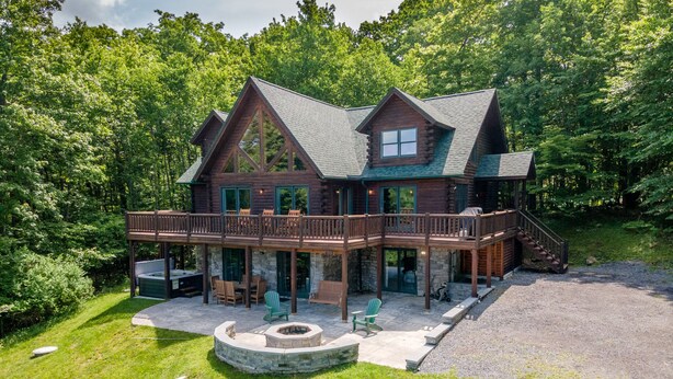 A log cabin with a covered patio, outdoor seating, and a fire pit. - Mountain Lodge w/ Fire Pit, Games & Lake Fun (Swanton)