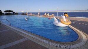 Una piscina con sillas de descanso y un flotador decorativo con forma de cisne.