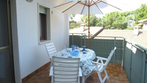 Une terrasse avec une table dressée pour deux personnes, des chaises et un grand parasol.