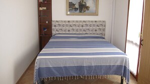 Une chambre à coucher avec un lit, une bibliothèque, un tableau et une porte.