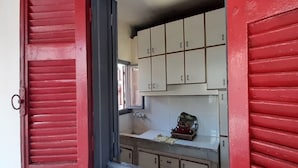 A kitchen with red shutters, white cabinets, and a sink. - Monatop  Studio Furn El Chebbek (Forn El Chebbak)