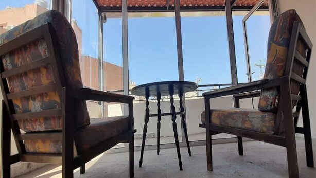 A patio area with two wooden chairs and a small round table. - Monatop  Studio Furn El Chebbek (Forn El Chebbak)