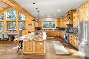 A spacious kitchen with wooden cabinets, a large island, and a stone countertop.