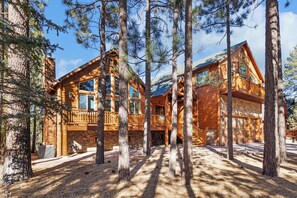 A log cabin with a stone foundation, wooden balconies, and a stone fireplace.