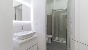 A modern bathroom with a white sink, a toilet, and a glass shower enclosure. - Italianway - Garibaldi 104 C (Milan)